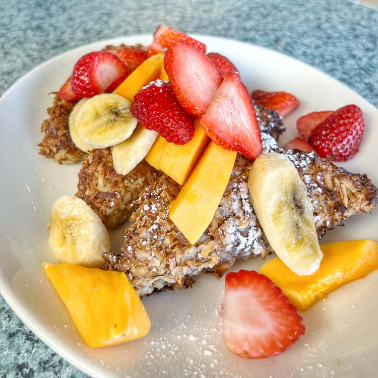 Sliced mango, strawberry and banana tumble over sliced of toasted coconut-encrusted French toast. 