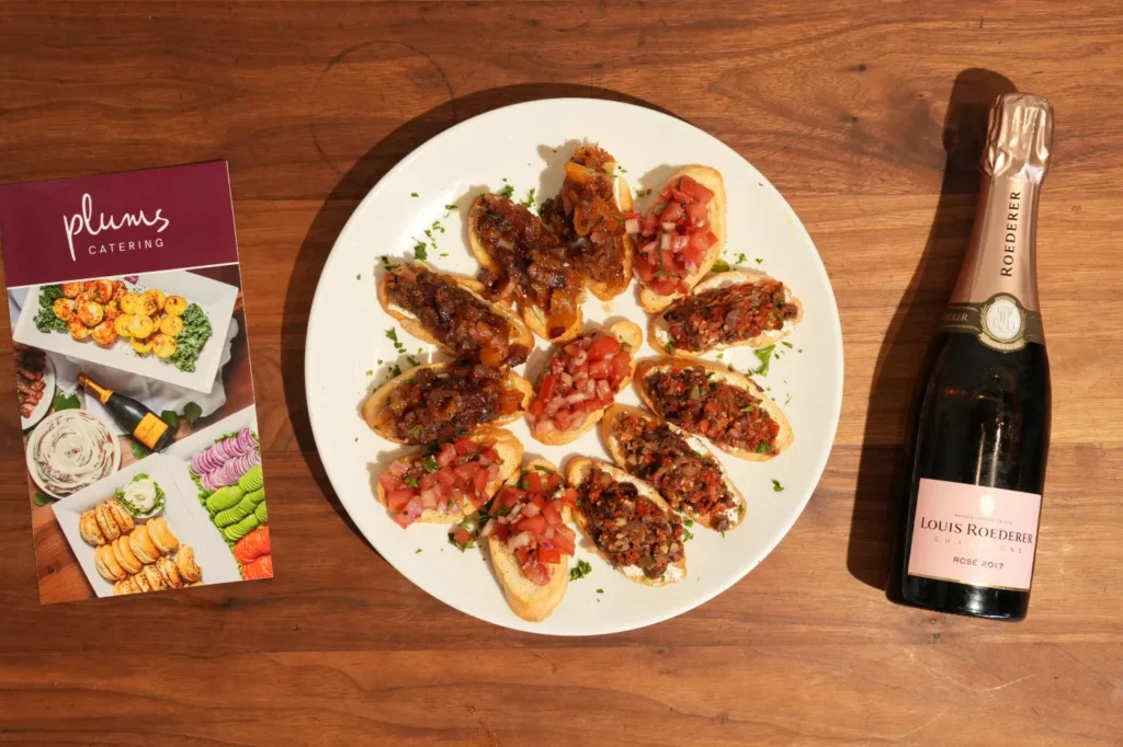Bruschetta platter beside champagne bottle and catering brochure