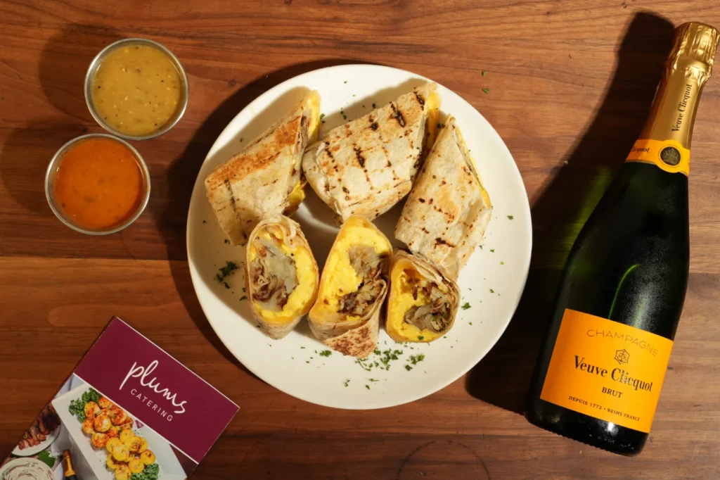 Grilled breakfast wraps with sauces and champagne on wooden table