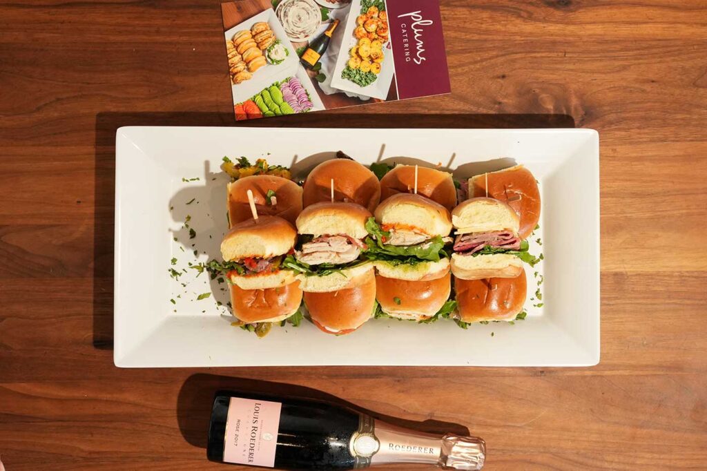 Platter of assorted sandwich sliders on wooden table